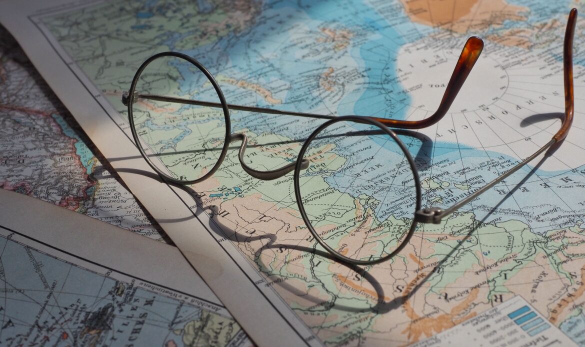 Round vintage eyeglasses resting on a vibrant historical world map, capturing a sense of exploration.