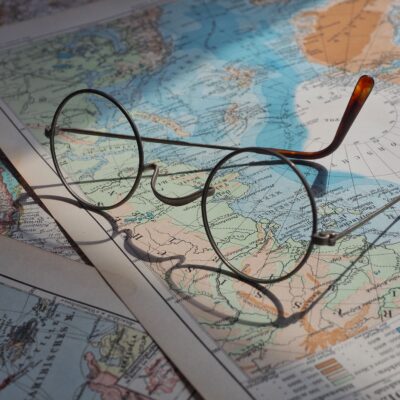 Round vintage eyeglasses resting on a vibrant historical world map, capturing a sense of exploration.