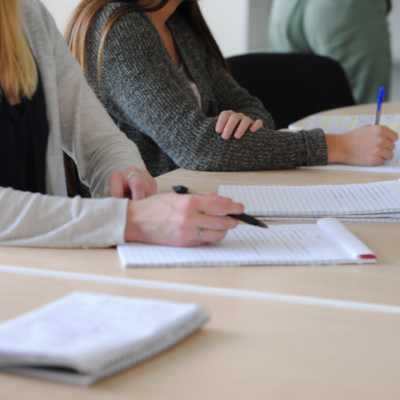 Group of students writing notes at a meeting in a well-lit classroom.