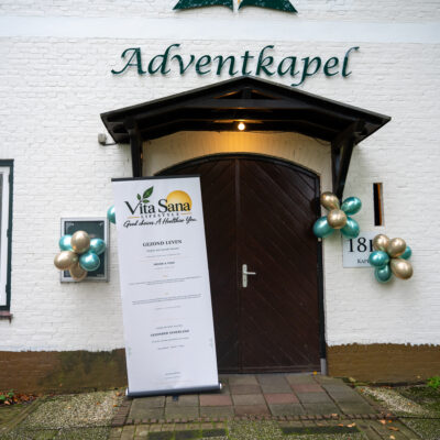 Avendkapel aan de buitenkant met een banner van Vita Sana en groen goude ballonnen.