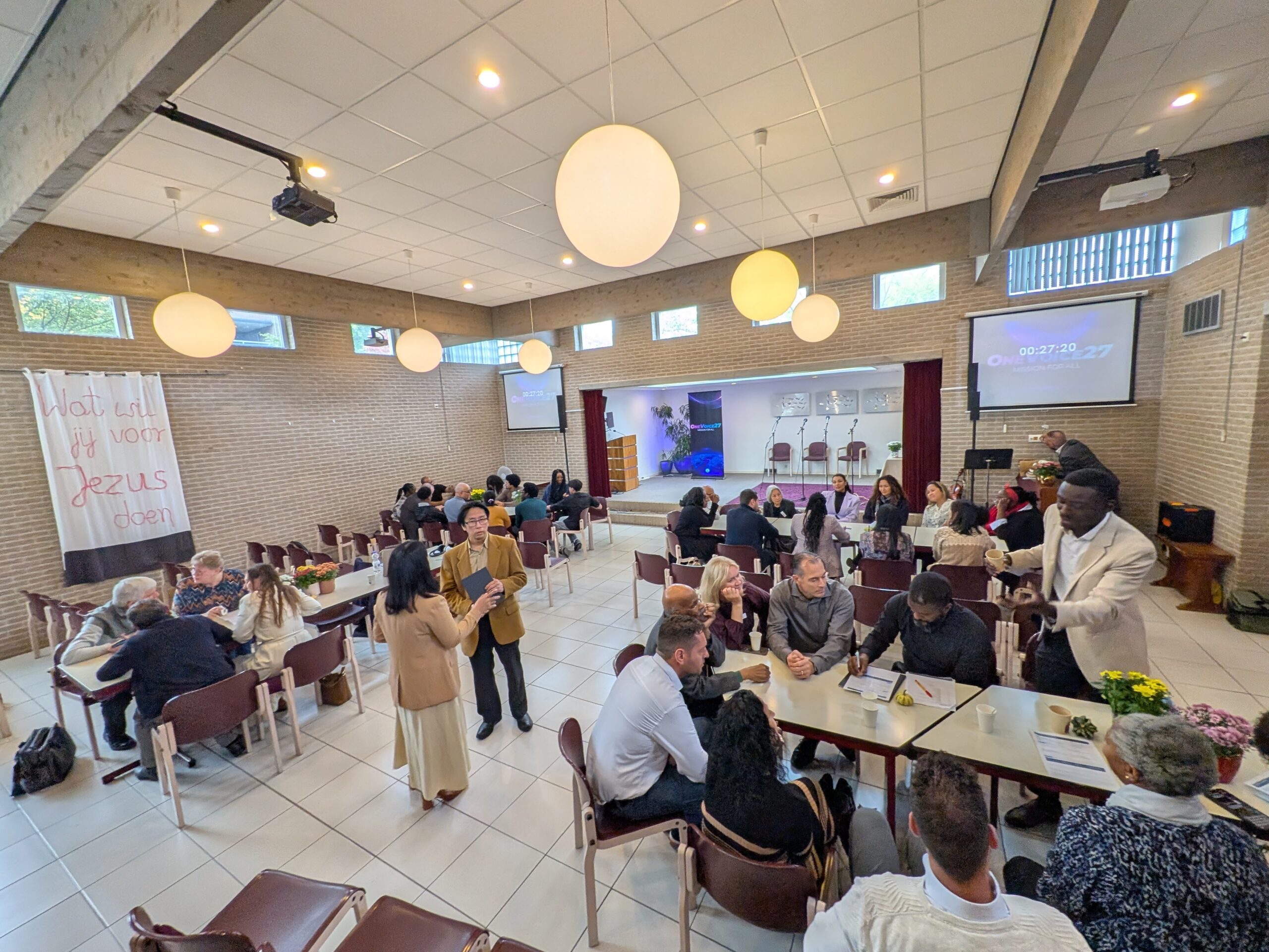 groep mensen zitten in een capel in overleg met elkaar.